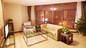 A modern living room with a sofa, armchair, and glass coffee table. - Best Western Yantai Hotel (Yantai)