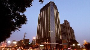 A tall, modern building with a glass facade, surrounded by a busy urban street at dusk. - Best Western Yantai Hotel (Yantai)