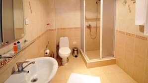 A bathroom with a sink, toilet, and glass-enclosed shower. - Boyuk Gala Hotel (Baku)