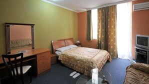 A hotel room with a bed, a desk, a chair, a TV, and a window with curtains. - Boyuk Gala Hotel (Baku)