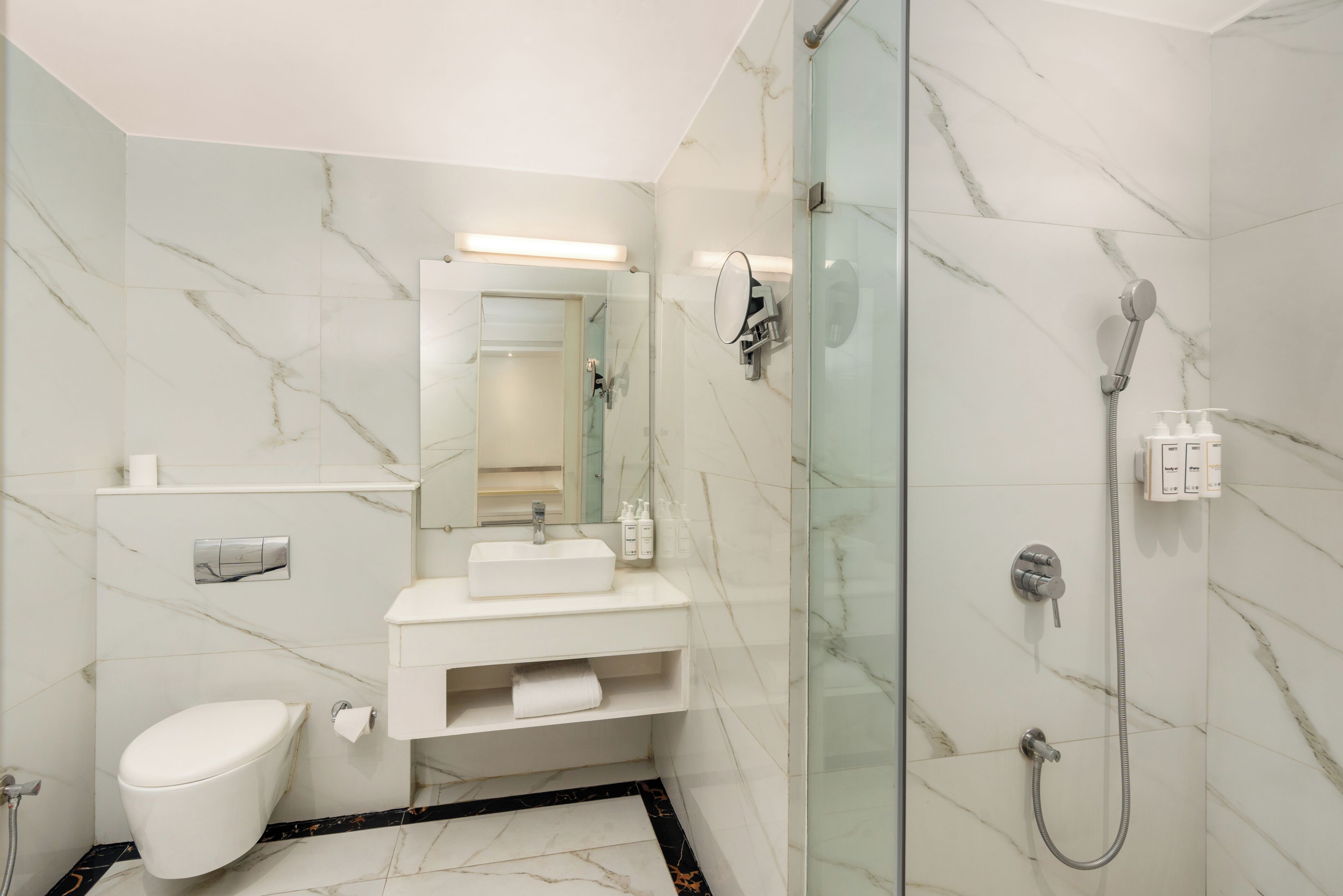 Un baño moderno con ducha de vidrio, lavamanos blanco y retrete.