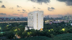 A high-rise hotel with a modern design, surrounded by greenery and a cityscape in the background. - Park Inn by Radisson New Delhi IP Extension (New Delhi)