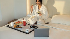A person sitting on a bed with a tray of breakfast items, a laptop, and a smartphone. - Park Inn by Radisson New Delhi IP Extension (New Delhi)