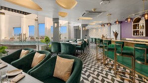 A restaurant with green upholstered chairs, a bar area, and a checkered floor. - Park Inn by Radisson New Delhi IP Extension (New Delhi)