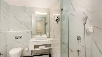 Ein modernes Badezimmer mit einer gläsernen Duschkabine, einem weißen Waschbecken und einer Toilette.