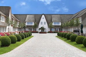 A courtyard with a central pathway leading to a building with a thatched roof. - Severin's Resort & Spa (Sylt)
