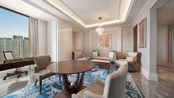 A spacious room with a round table, comfortable seating, a piano, and a large window with a city view.