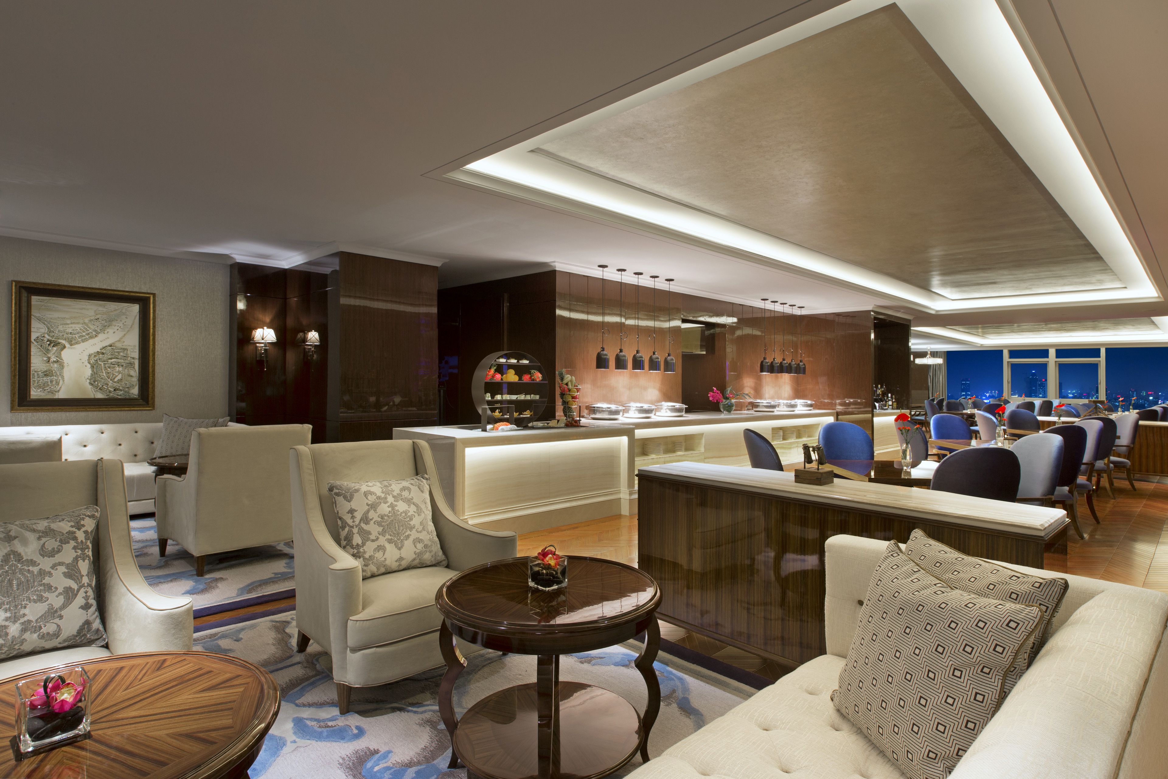 A modern hotel lobby with seating areas, a bar, and a view of the city.