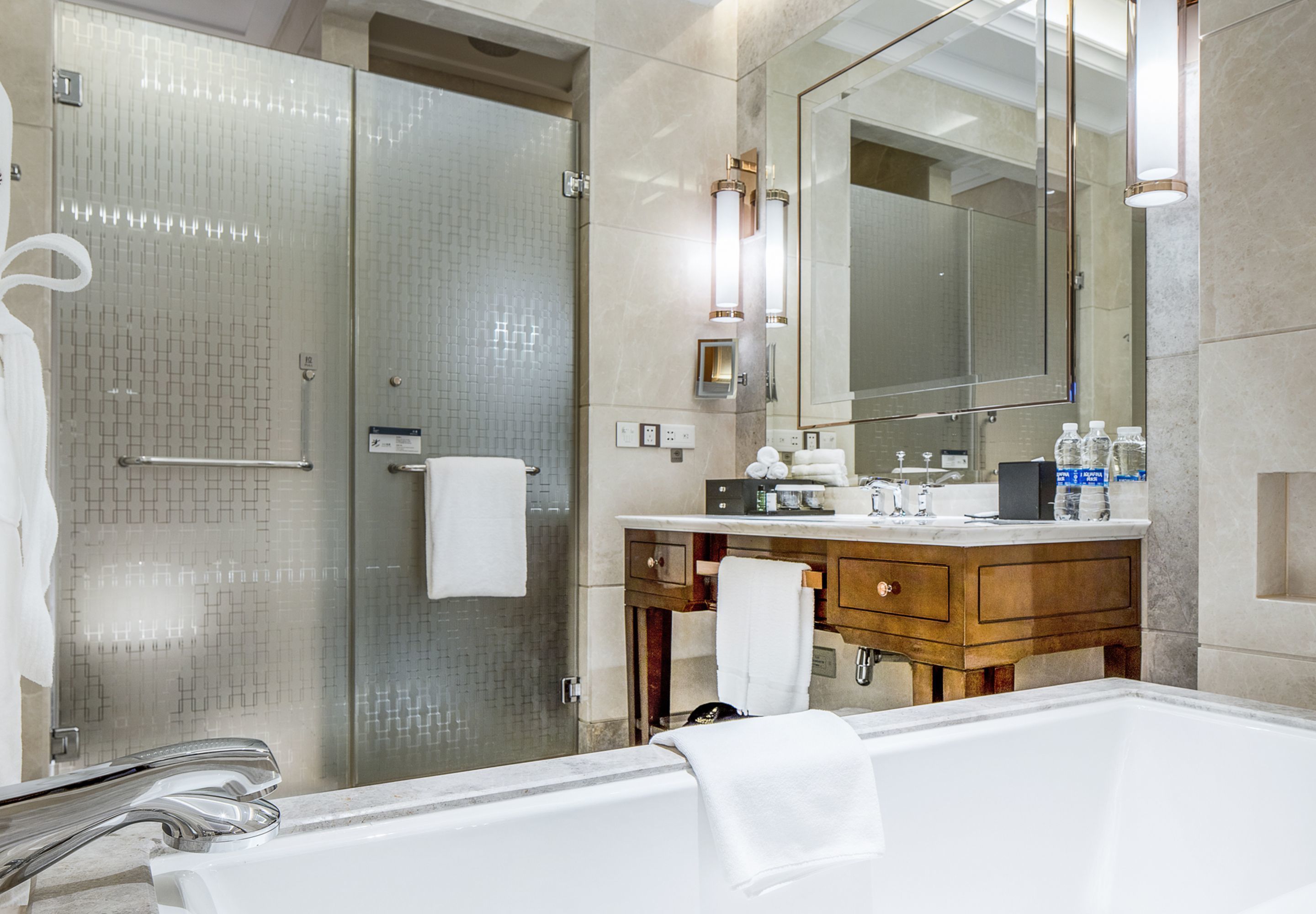 A modern bathroom with a glass shower enclosure, a wooden vanity, and a large mirror.