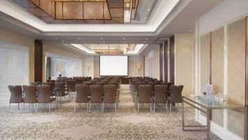 A conference room with a long table and chairs, a carpeted floor, and a large screen at the front.