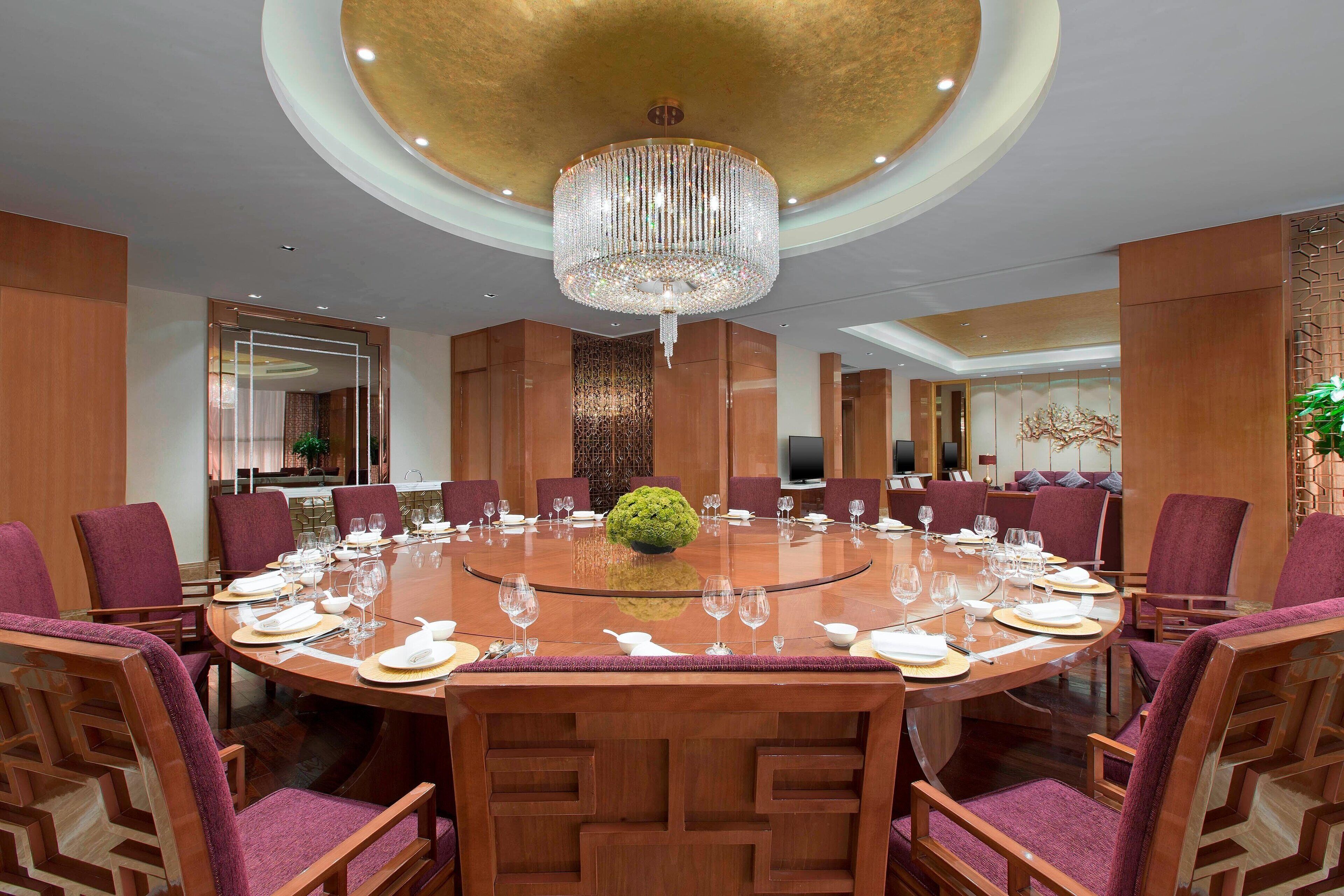 A conference room with a round table, purple chairs, and a chandelier.