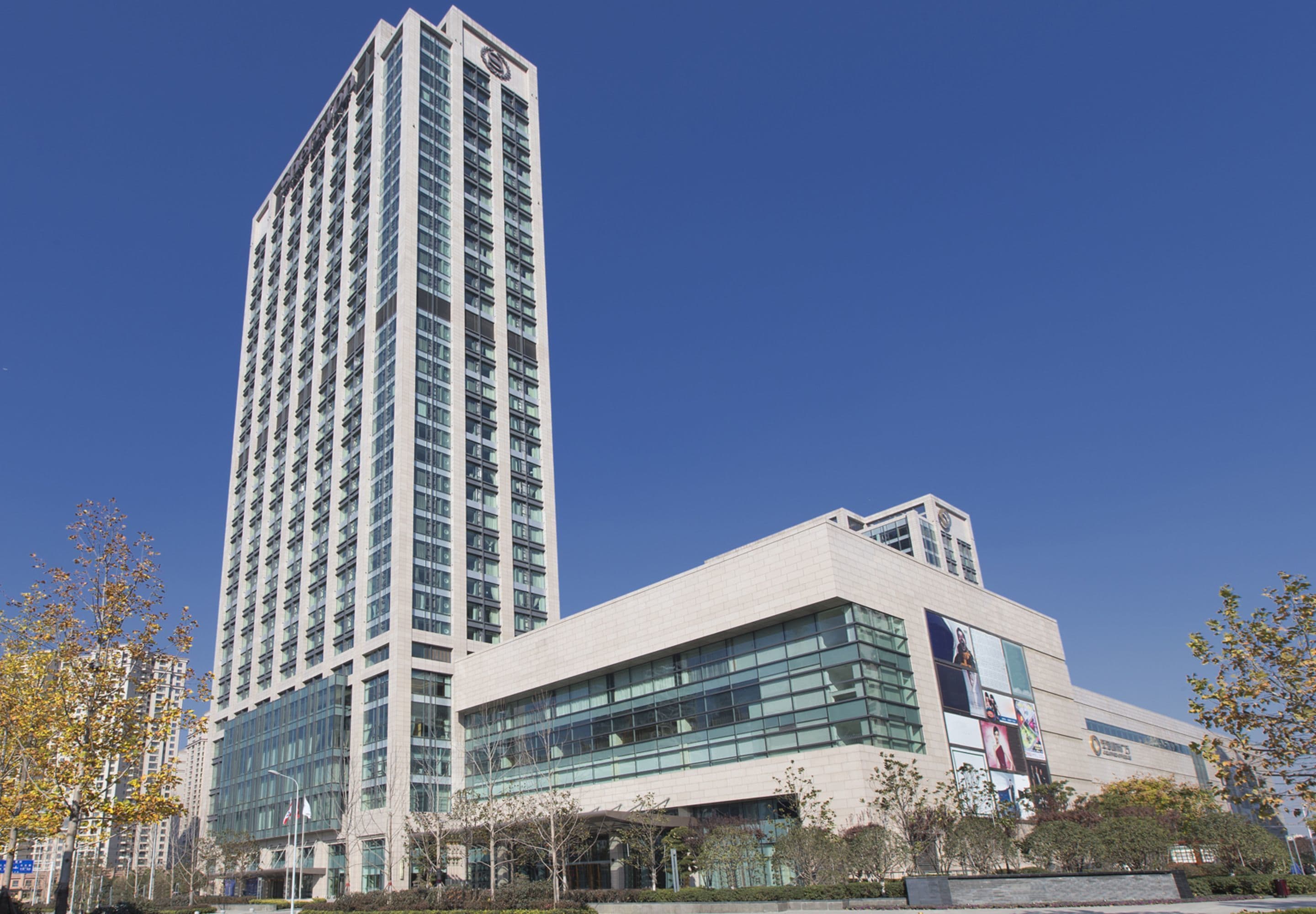 A modern high-rise building with a prominent glass facade and a smaller adjacent structure.