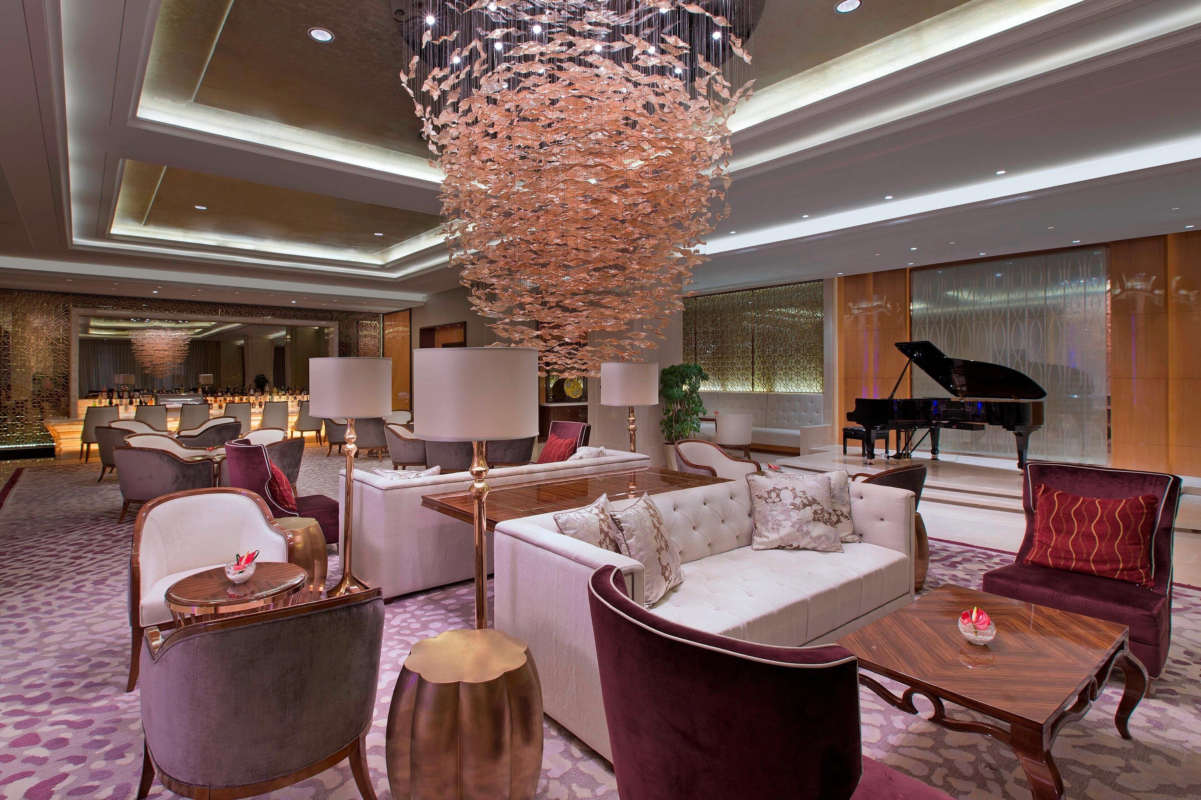 A spacious lobby with a grand chandelier, plush seating, and a grand piano.