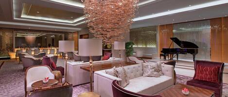 A spacious lobby with a grand chandelier, plush seating, and a grand piano.