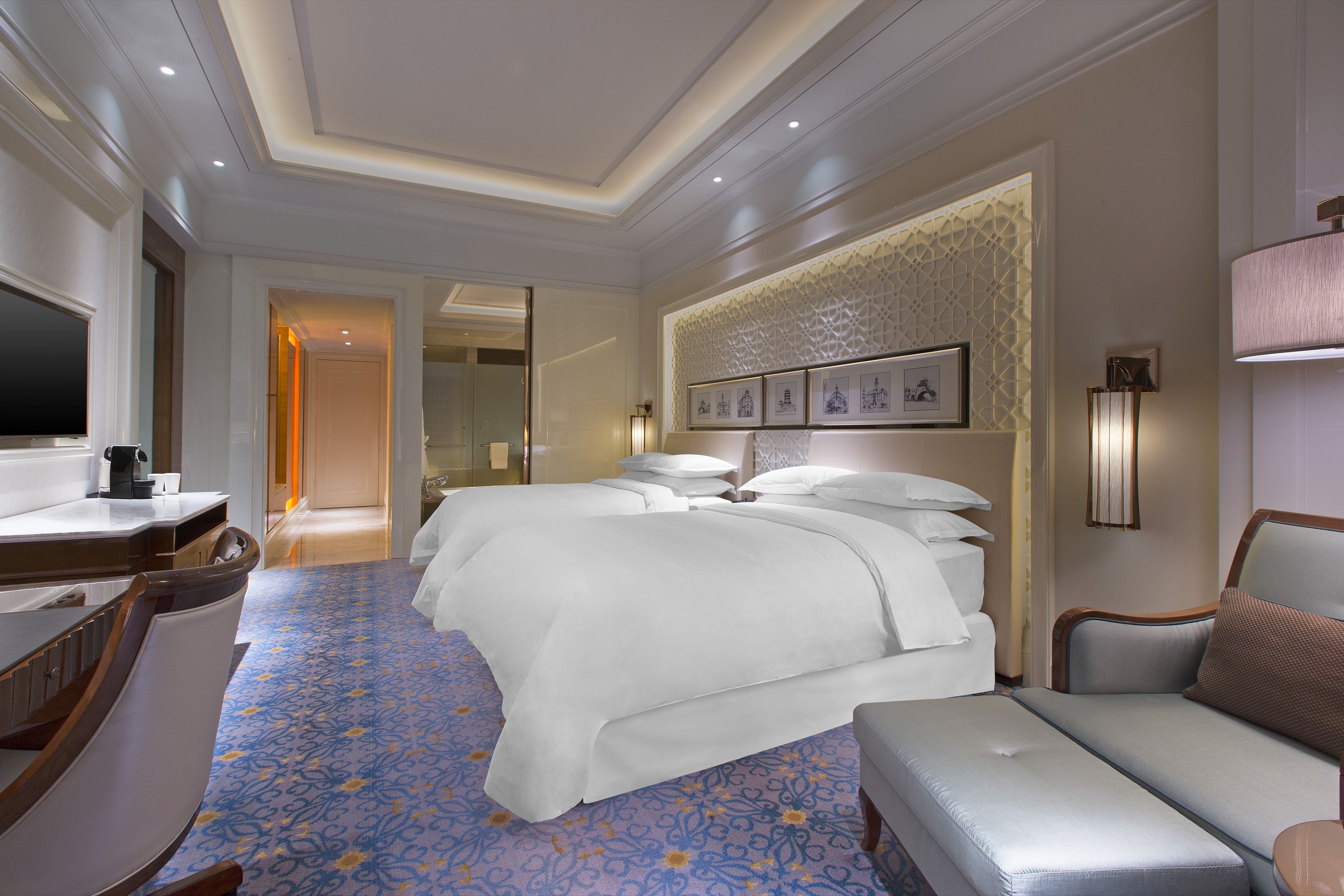 A hotel room with a large bed, a sofa, a desk, and a TV.