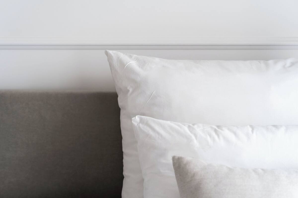 A room with a grey sofa and two white pillows against a white wall.