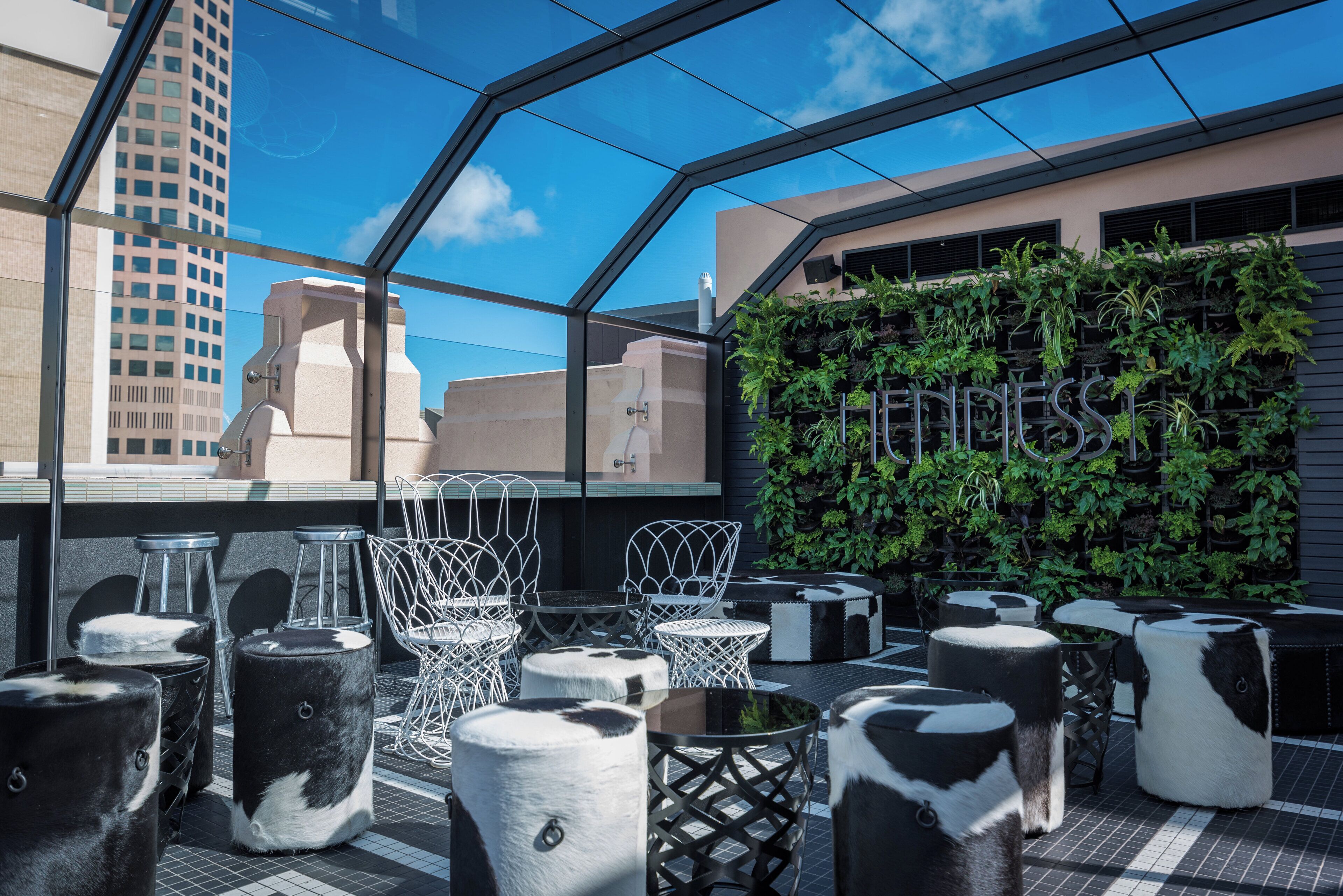A rooftop terrace with outdoor seating, a glass enclosure, and a vertical garden.