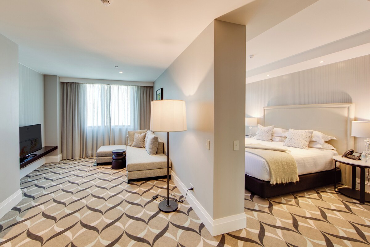 Une chambre d’hôtel avec un lit, un canapé, une télévision et une lampe.