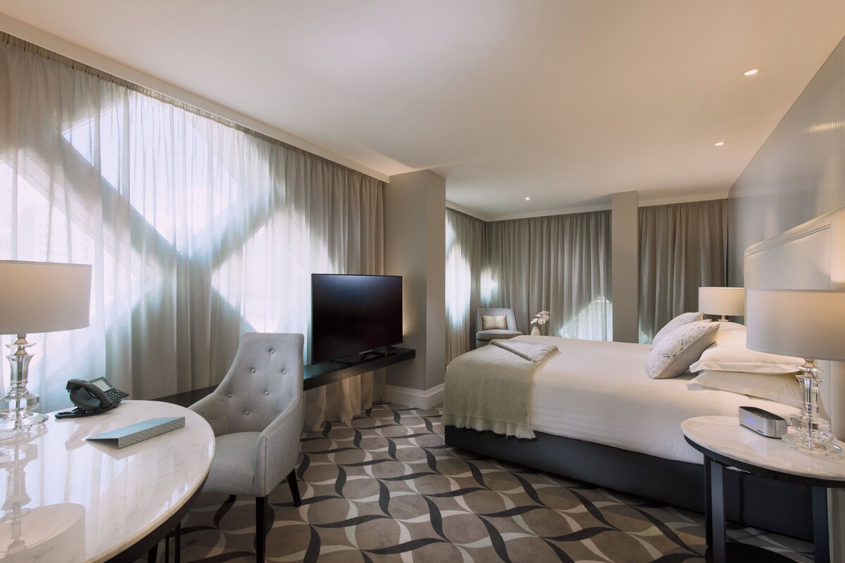 Une chambre d’hôtel comprenant un lit, un bureau avec une chaise, une télévision et une lampe.