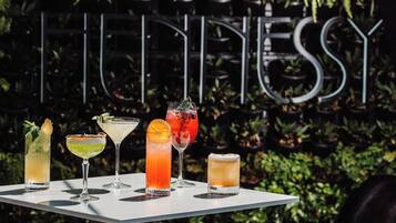 A table with five cocktails in front of a sign with the word "HENNESSY".