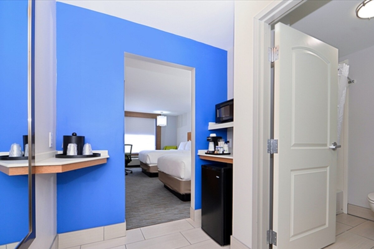 Een hotelkamer met een bed, een bureau, een magnetron en een toilet.
