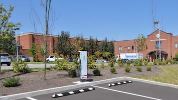 Een parkeerplaats met oplaadpunten voor elektrische voertuigen, een gebouw met de tekst 'Social Security Administration' en een vrachtwagen van 'Shred-it' voor leveringen.