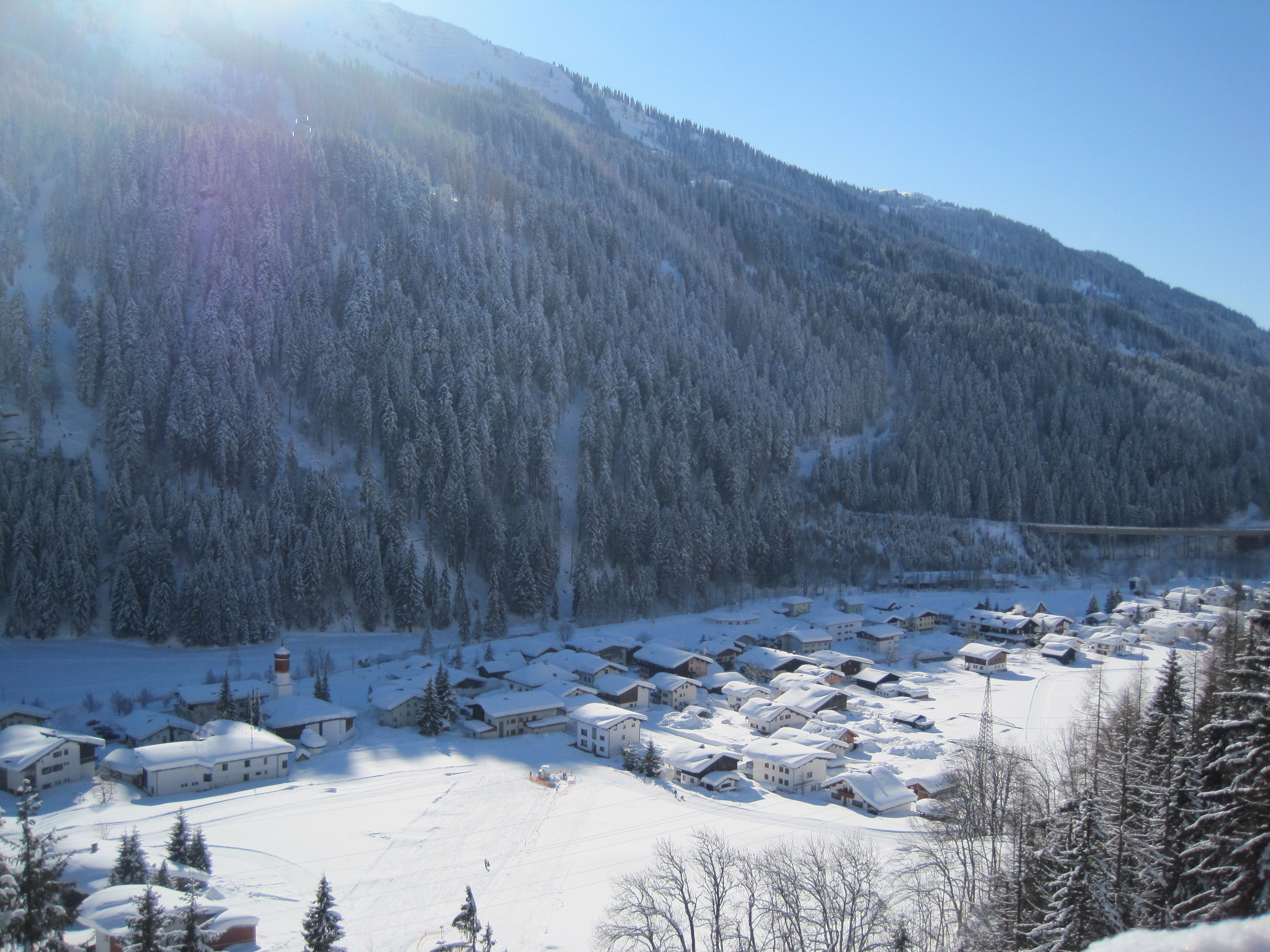 Ein schneebedecktes Dorf mit Häusern und einem Berg im Hintergrund.