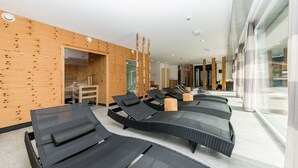 A modern indoor pool area with black lounge chairs and wooden walls. - Alpine Lodge Klösterle am Arlberg (Klösterle am Arlberg)