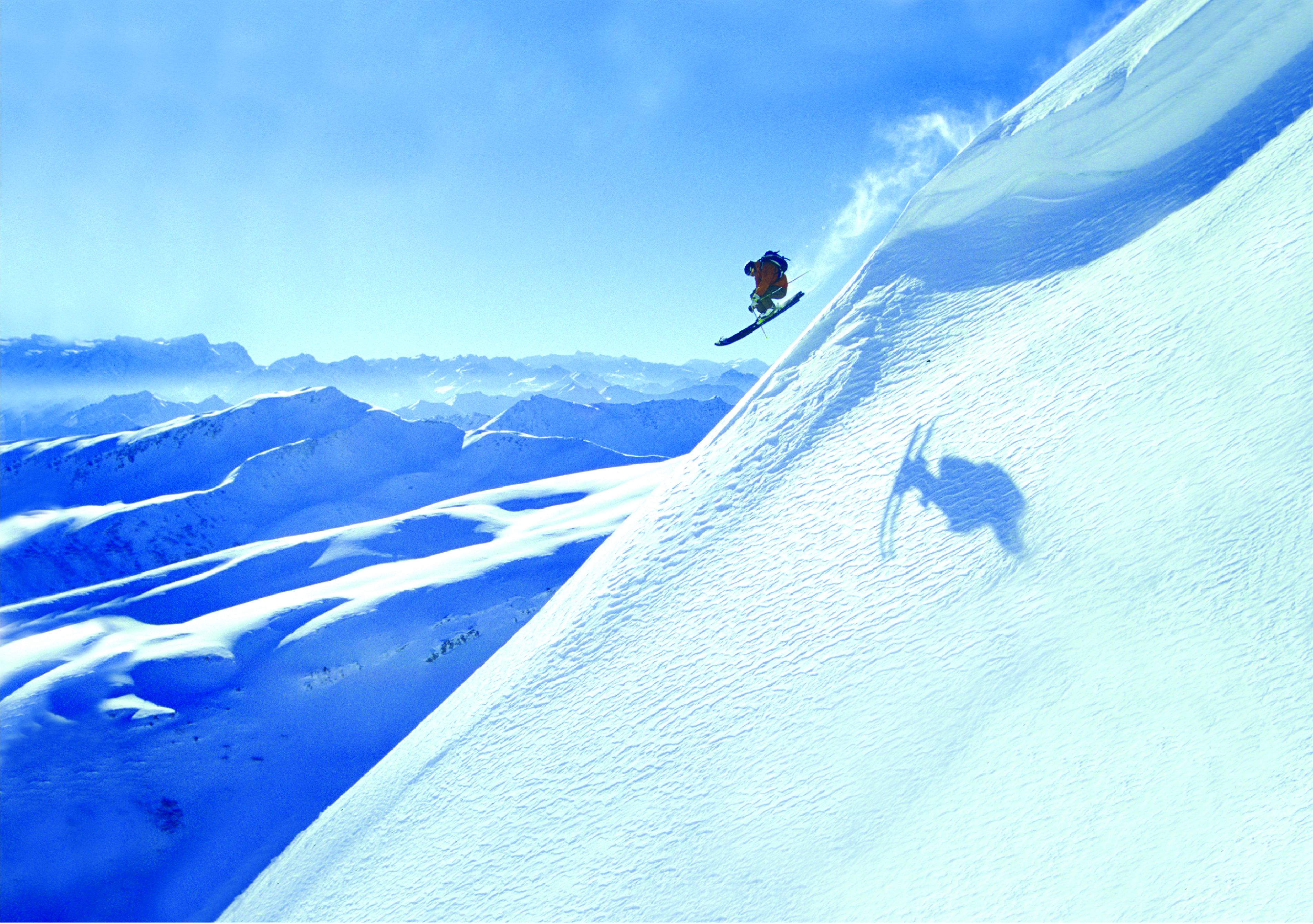 Un snowboarder realizando un salto en una ladera nevada de montaña.