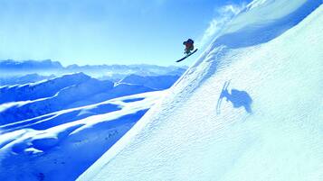 Un snowboarder realizando un salto en una ladera nevada de montaña.
