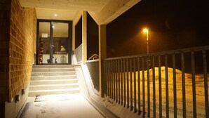 A staircase leading to a building entrance at night, with a metal railing and a snow-covered ground. - Alpine Lodge Klösterle am Arlberg (Klösterle am Arlberg)