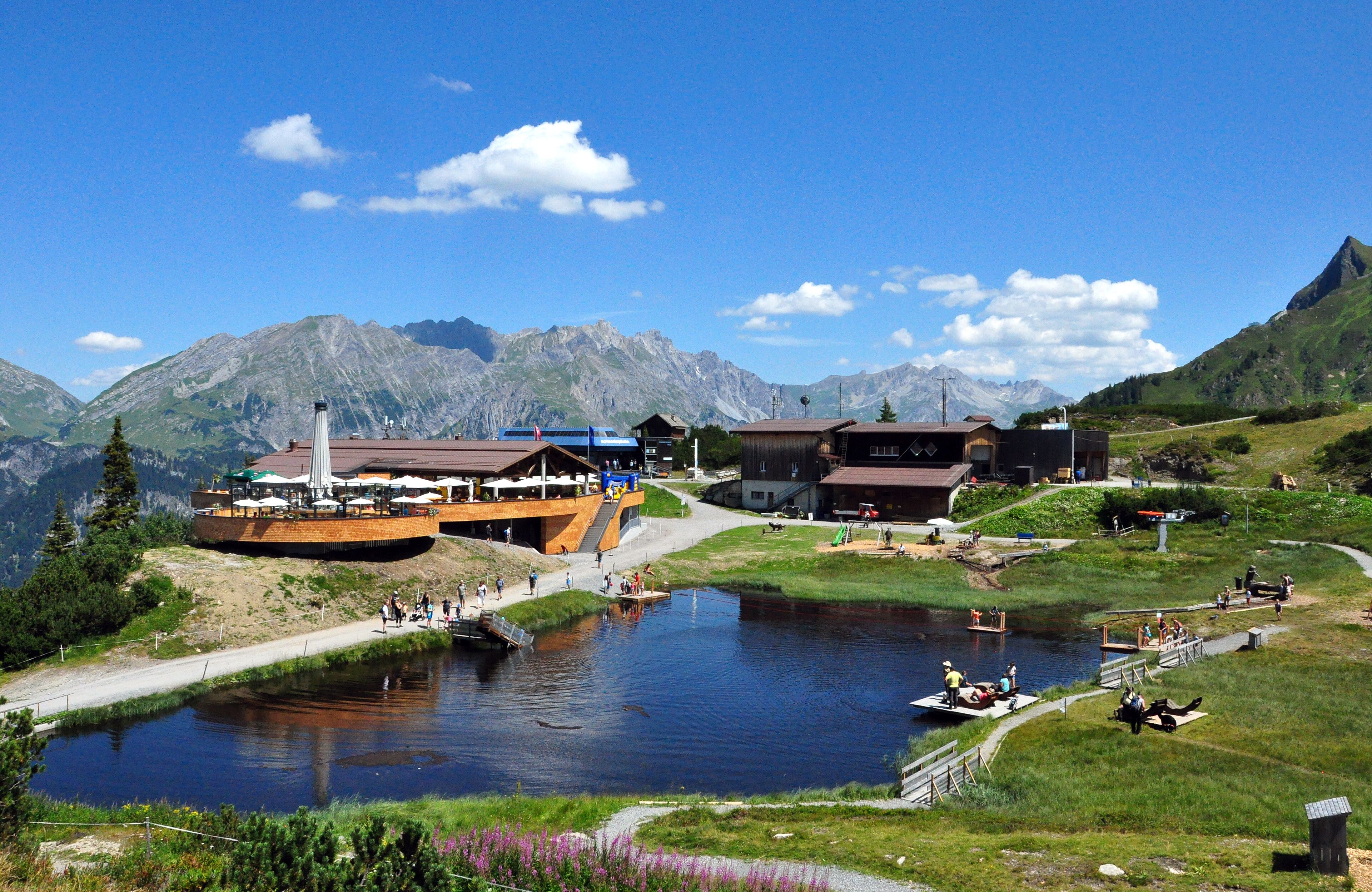 A lakeside resort with a boat dock, outdoor seating, and mountain views.