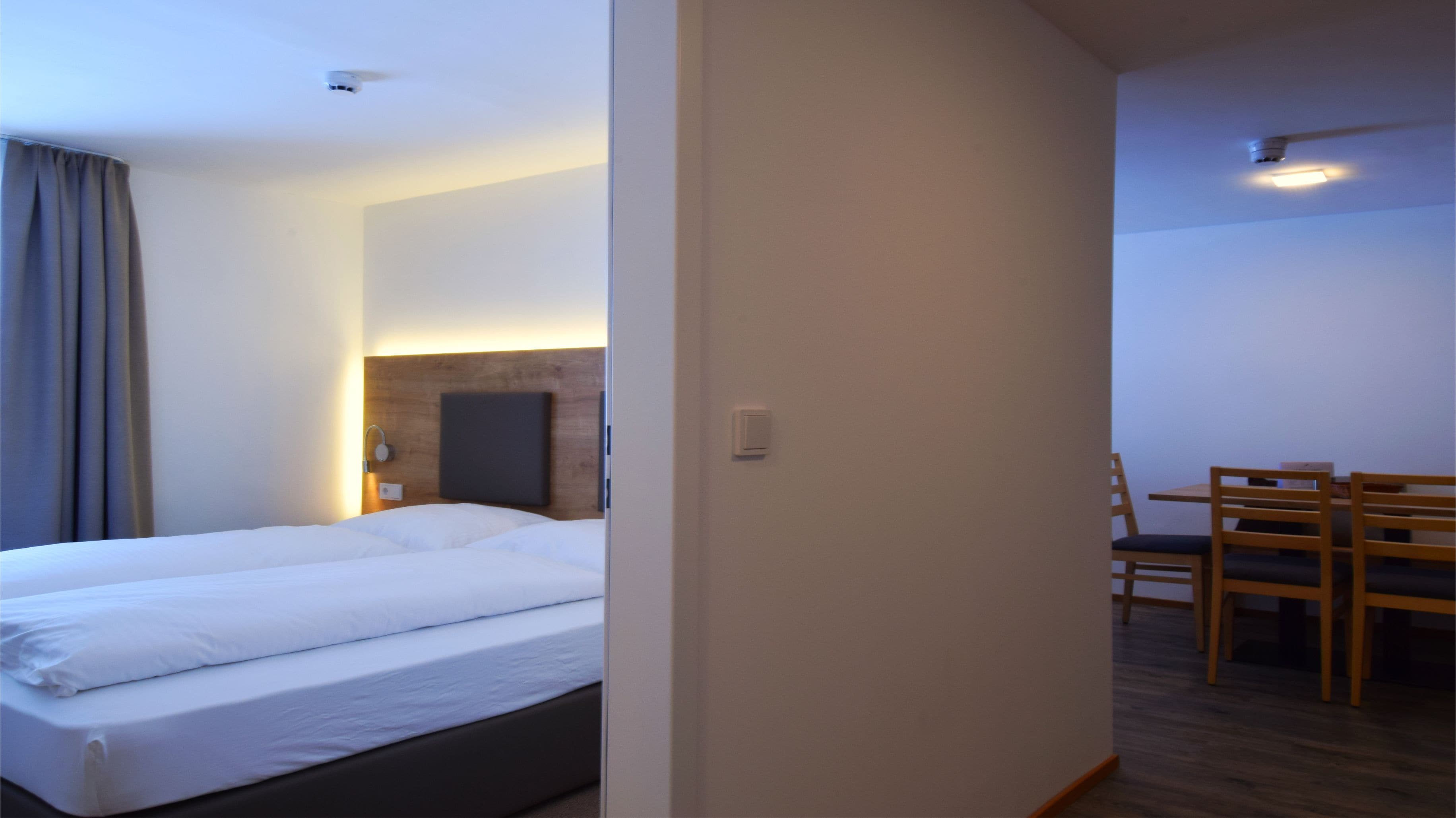 Quarto de hotel com cama, escrivaninha e cadeira.
