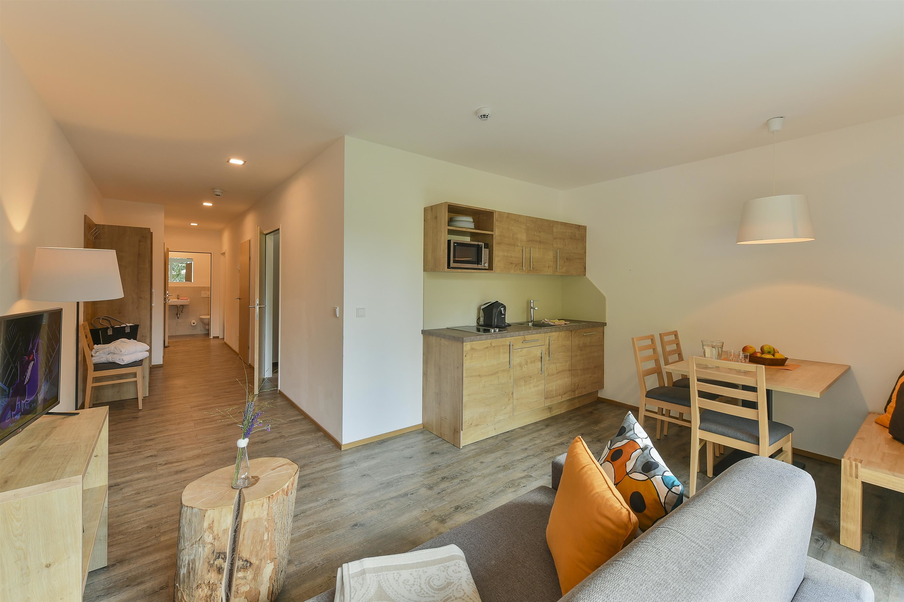 A modern living area with a sofa, dining table, and kitchenette.