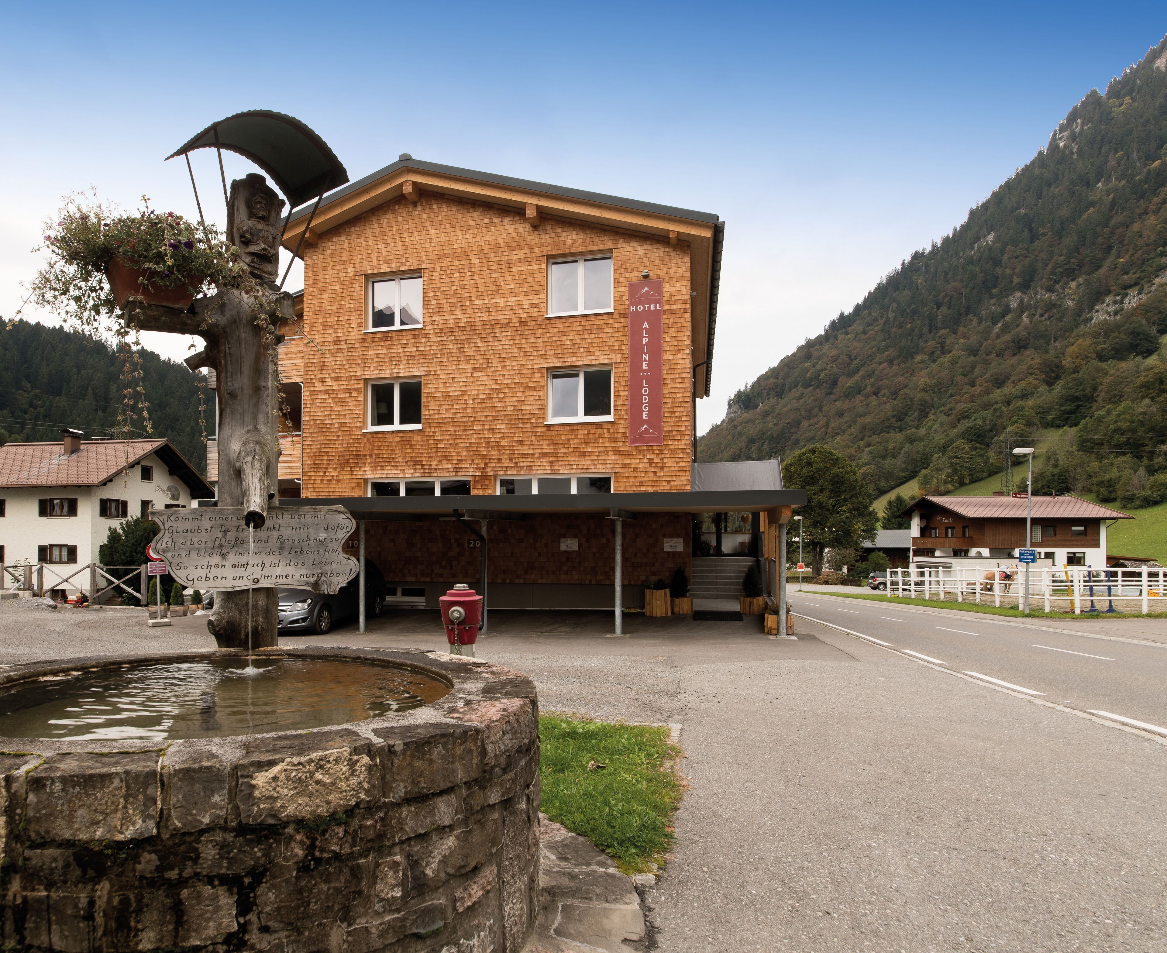 A hotel with a brick facade, a sign indicating it is a hotel, and a mountain backdrop.