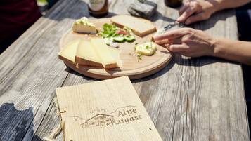 Une table en bois, sur laquelle on trouve une planche à fromage, des bouteilles et une plaque en bois.