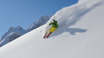 A skier on a snowy slope with a clear sky.