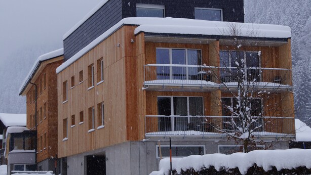 A multi-story building with a wooden facade and balconies, surrounded by snow. - Alpine Lodge Klösterle am Arlberg (Klösterle am Arlberg)