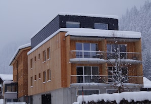Un edificio de varios pisos con fachada de madera y balcones, rodeado de nieve.