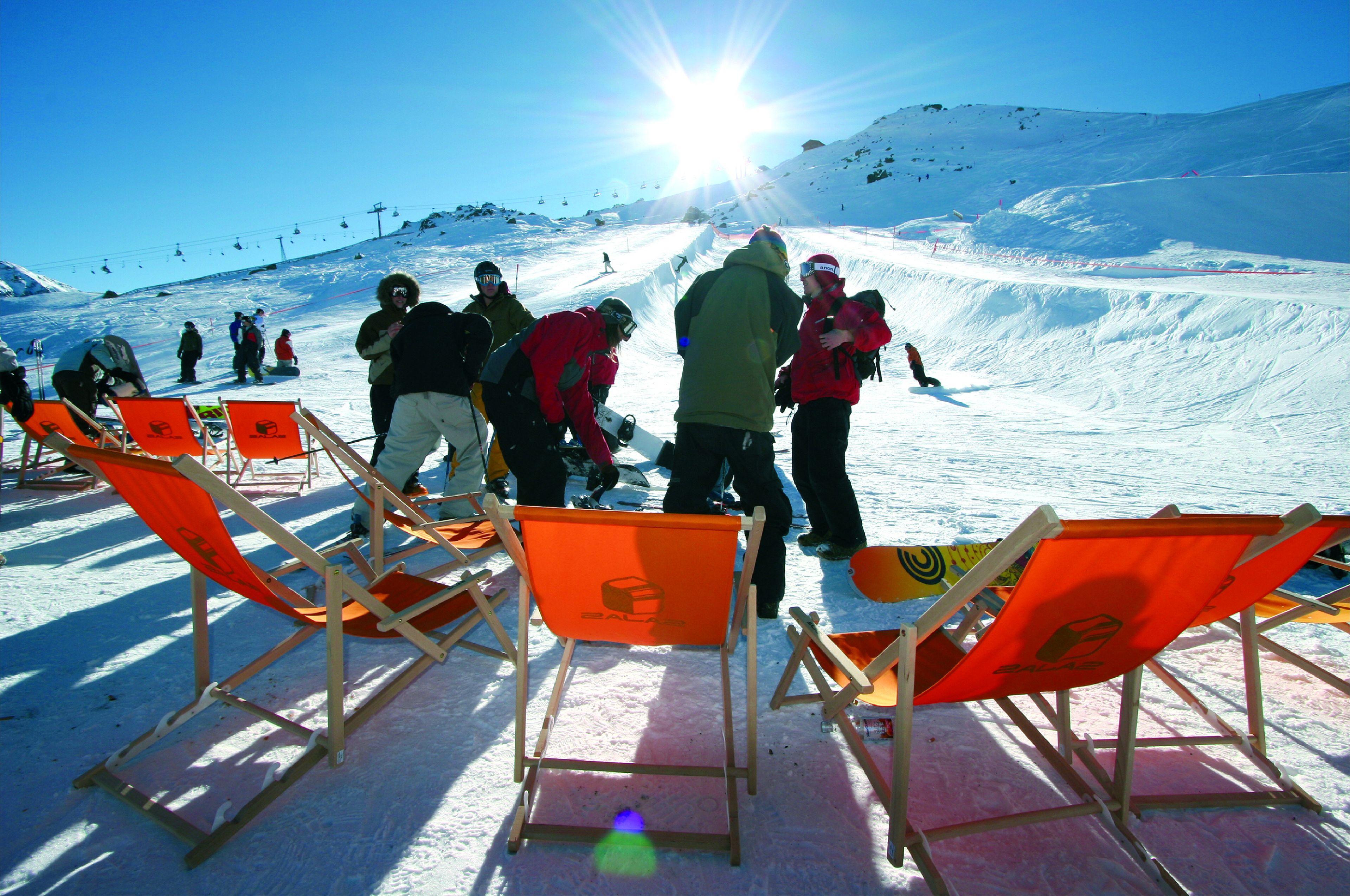 Een skipiste met oranje skistolen en mensen die zich voorbereiden om te skiën.