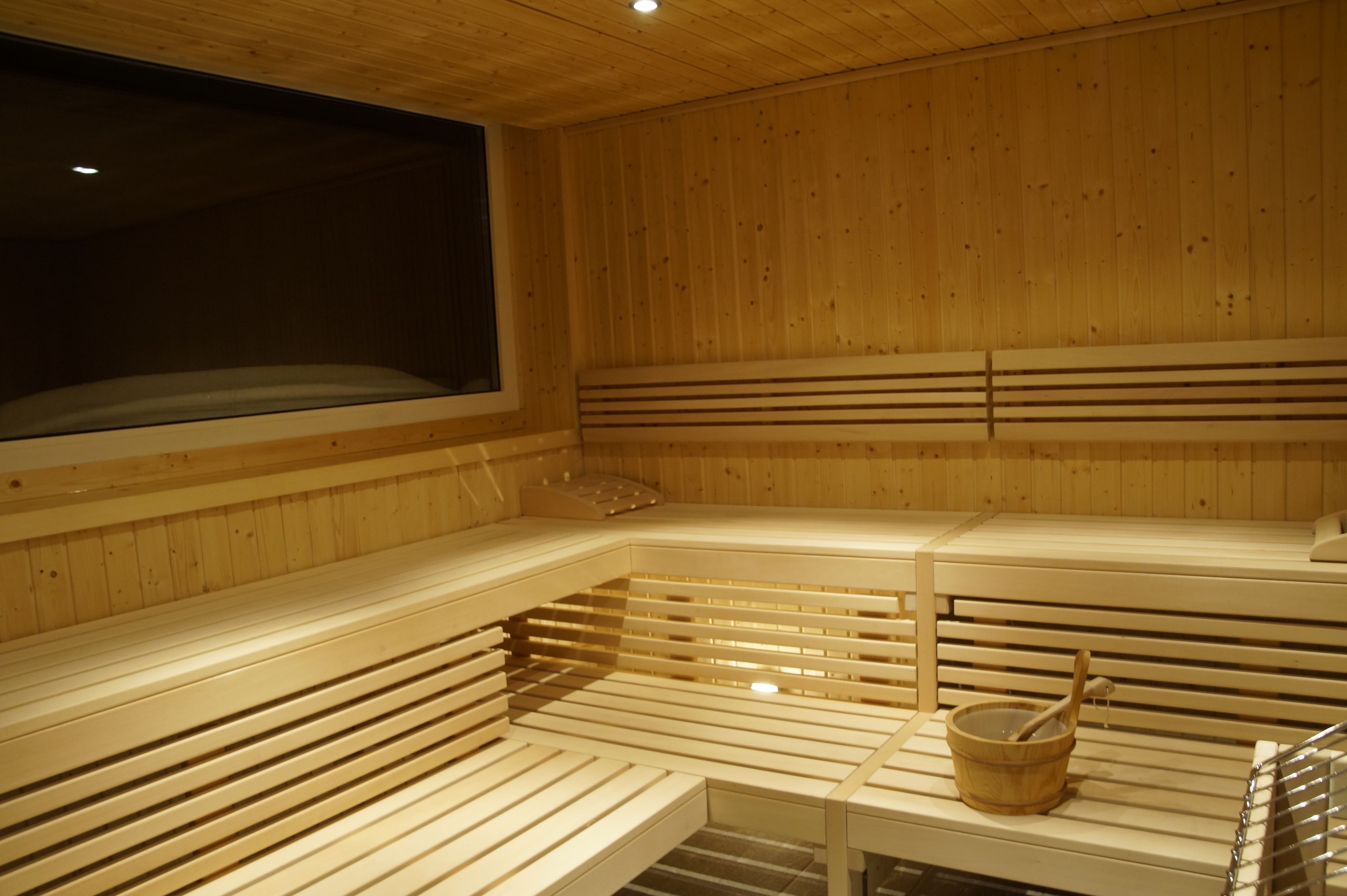 Una sauna con bancos de madera y un balde de madera.