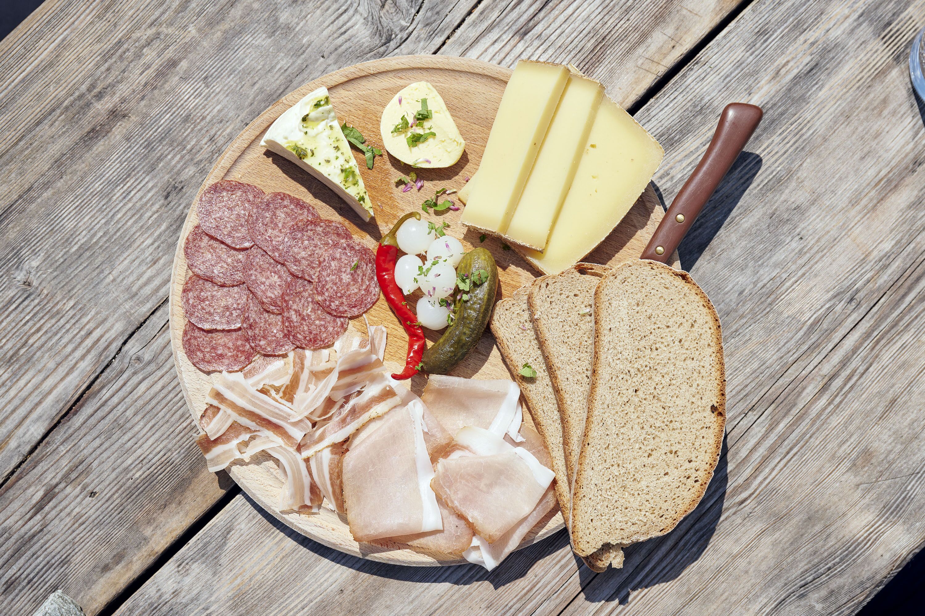 A charcuterie board with various meats, cheeses, and bread on a wooden table.