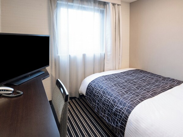 Una habitación de hotel con una cama, televisión, escritorio y teléfono.