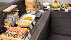 Un buffet proposant une variété de plats, notamment des saucisses, des nouilles et des salades.