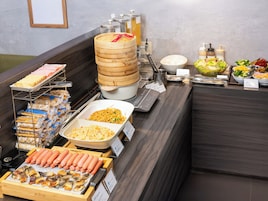 Un bufé con diversas opciones de comida, como salchichas, fideos y ensaladas.