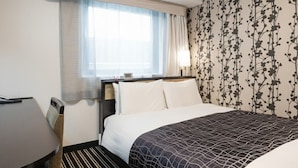 Une chambre d’hôtel avec un lit, un bureau et une fenêtre avec des rideaux.