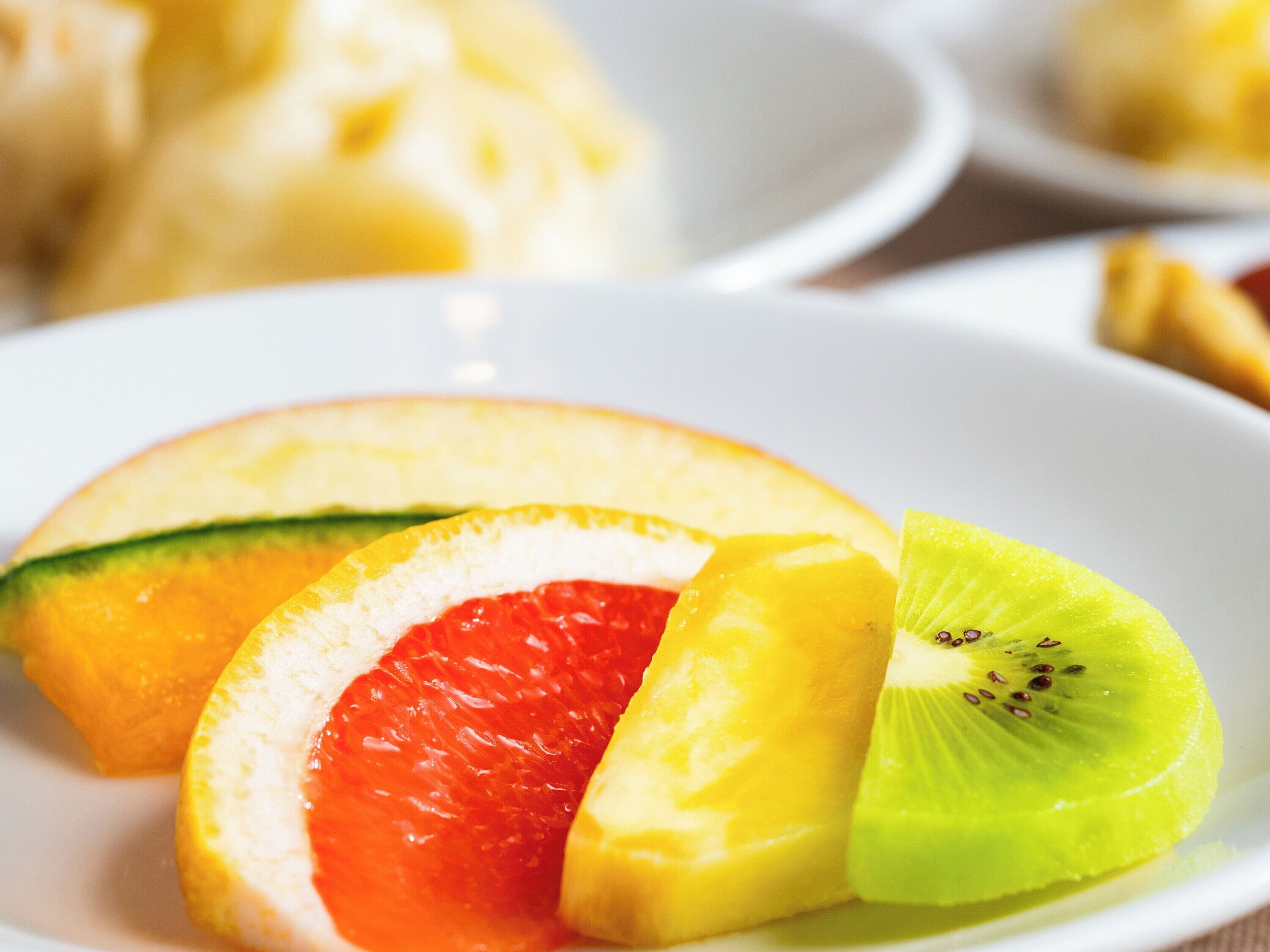 Een bord met partjes grapefruit, kiwi en een plak meloen.