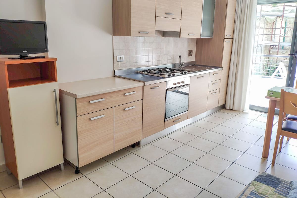 A modern kitchen with light wood cabinets, a gas stove, and a built-in oven.