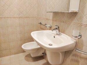 A bathroom with a white sink, a toilet, and a mirror above the sink.