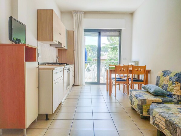 Ett kompakt bostadsutrymme med ett litet kök, en matplats och en soffa.
